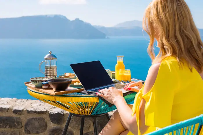 A woman on her computer next to the sea